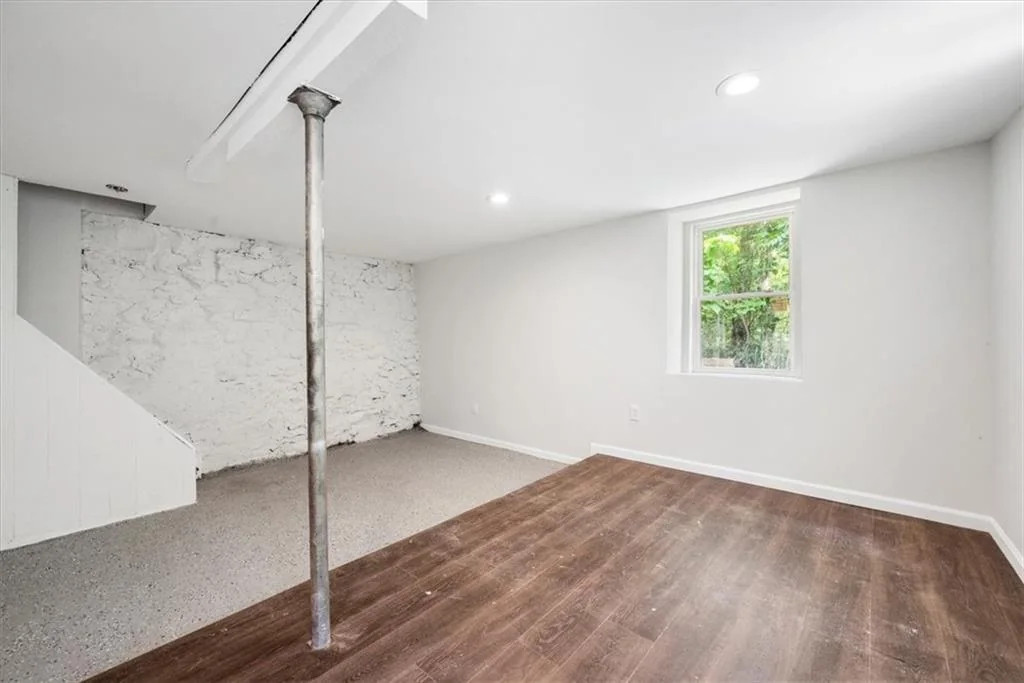Finished lower-level room with recessed lights and masonry wall