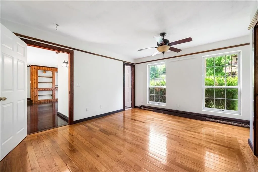 Finished bedroom with hardwood flooring and two windows