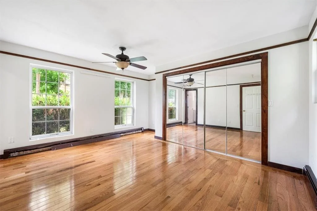 Large bedroom with hardwood flooring and mirrored closet doors