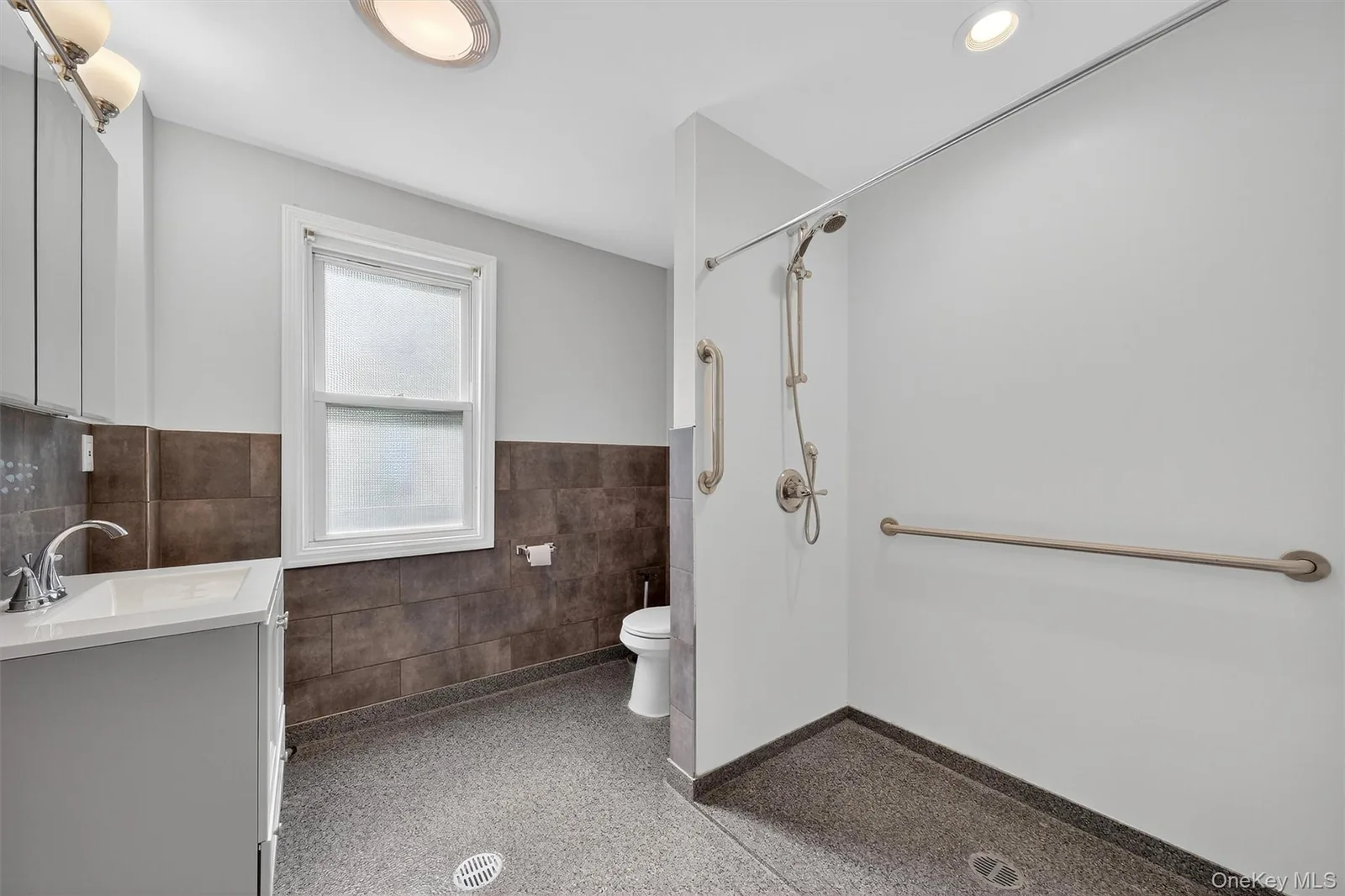 Completed accessible bathroom with open shower and grab bars