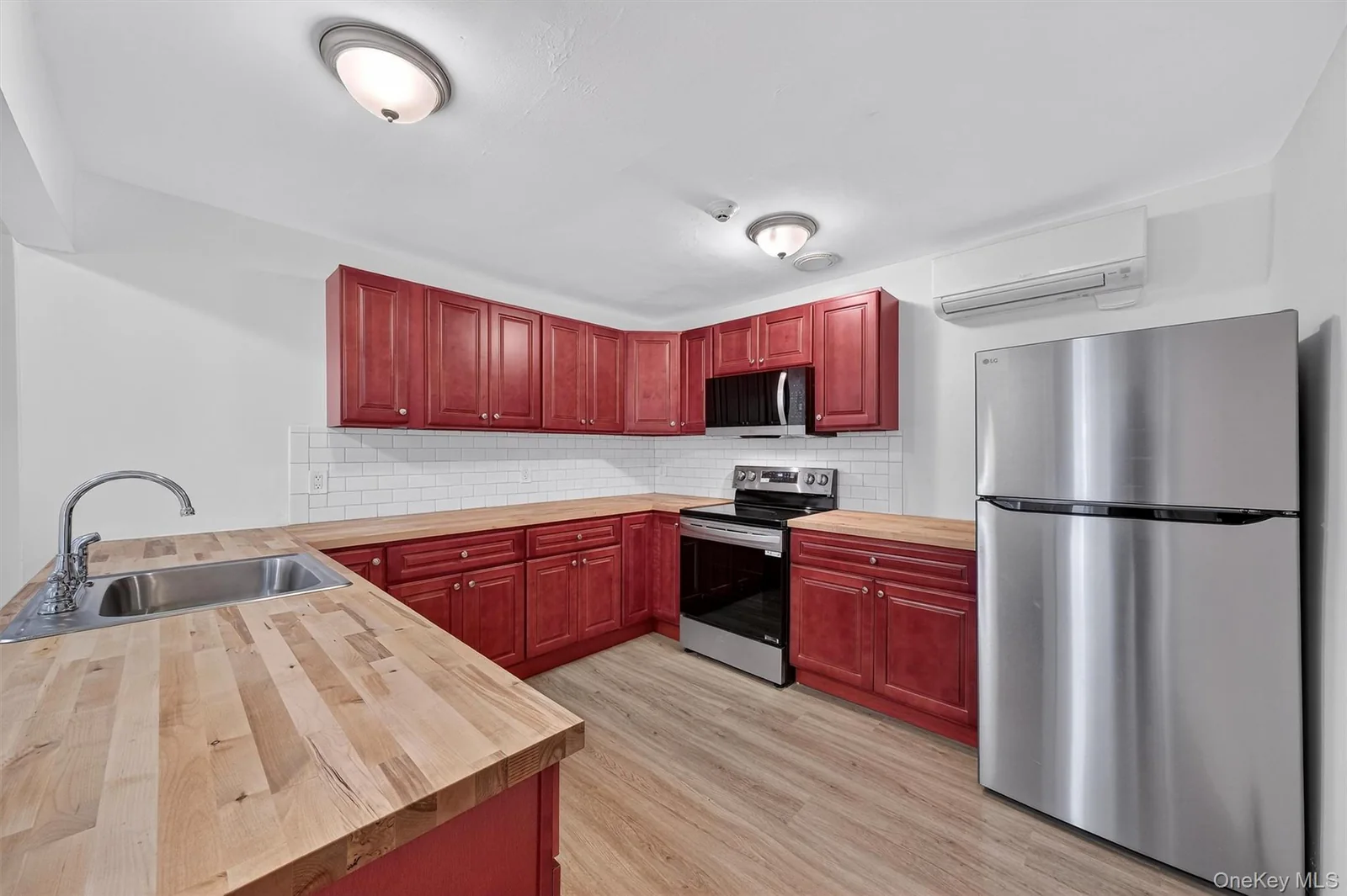 Completed second-floor kitchen with red cabinetry and stainless appliances